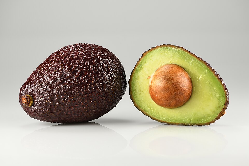 whole and halved Hass avocado with pit